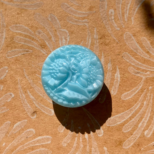 blå knap i glas med design af to blomster 